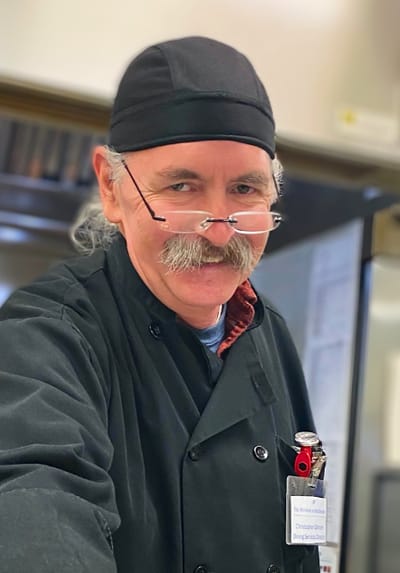 Chef with glasses smiling in the kitchen
