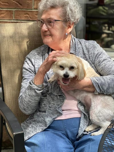 A resident holding a small dog while seated
