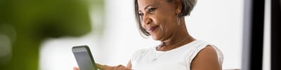 Senior woman comfortably using a smartphone indoors