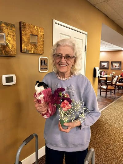Resident holding a kitten and flowers in the facility interior
