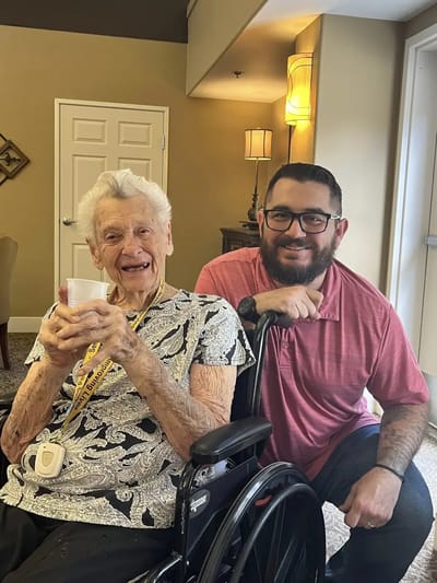 Elderly woman smiling with a staff member in a common area