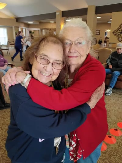 Two residents embracing in a cozy common area