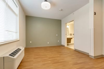 Empty resident room with wooden flooring and natural light