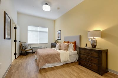 Bright resident room with bed and chair