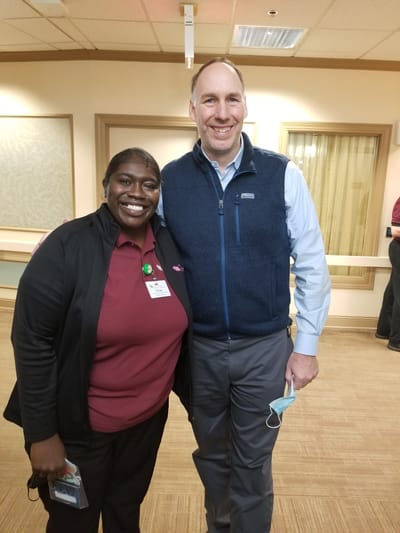 Staff member posing with a visitor in a common area