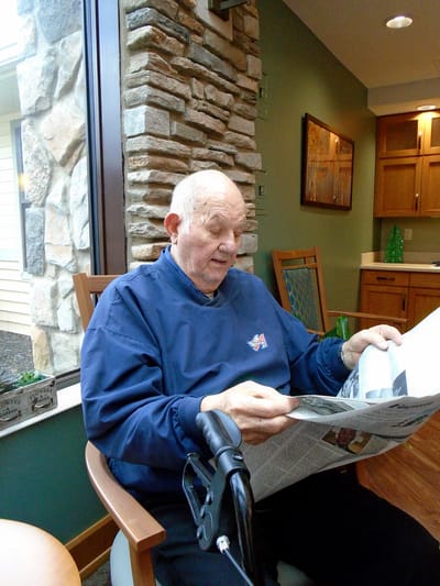 Resident reading a newspaper in a cozy common area