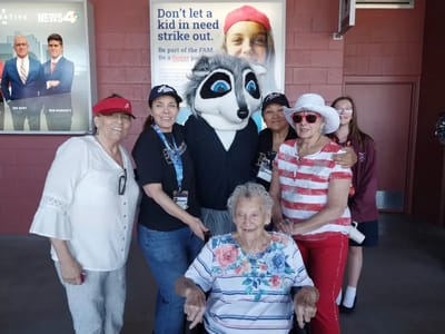 Residents and staff posing with a mascot at an event.