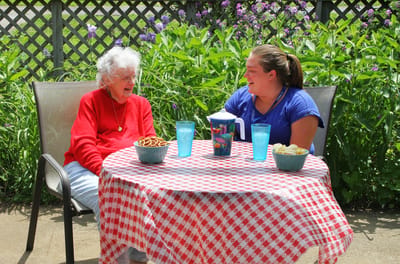 A resident enjoying snacks with a staff member outdoors
