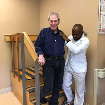 Staff assisting a resident on stairs inside the facility