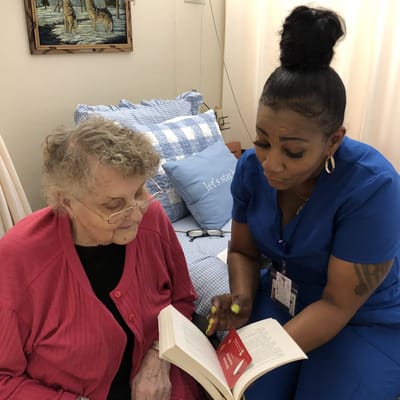 Staff member reading with resident in a cozy room
