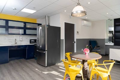 Bright kitchen area with yellow chairs and a table