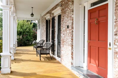 Front porch with chairs and a red door