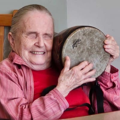Resident smiling with a drum in a common area