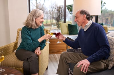 RiverSpring Living, nursing home in Bronx, NY — Seniors toasting with drinks in a cozy lounge
