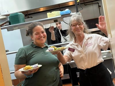 Staff and resident serving food in the kitchen