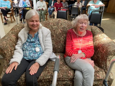 Two smiling residents sitting on a couch in a social area