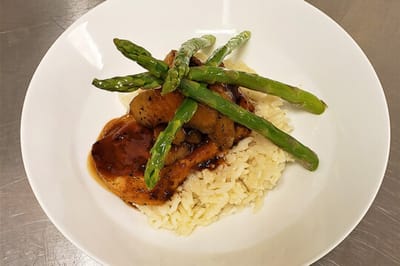 A plated meal with chicken, rice, and asparagus