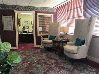 A cozy lounge area with armchairs and a view of the reception desk