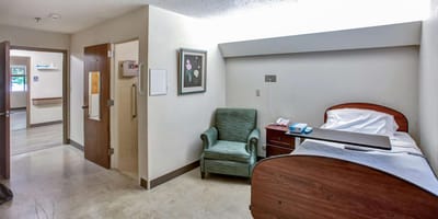 A private resident room with a bed and chair