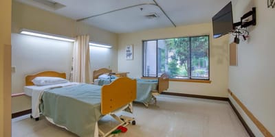 A pair of hospital beds in a private resident room