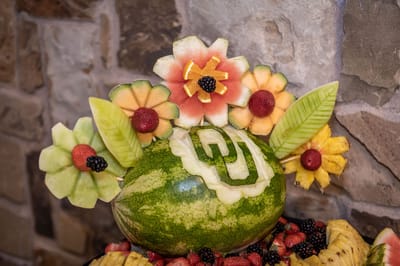 A decorative fruit arrangement with flowers and a logo
