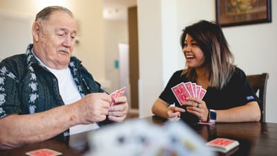 A resident and staff member playing cards together