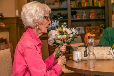 Elderly resident holding flowers in a common area