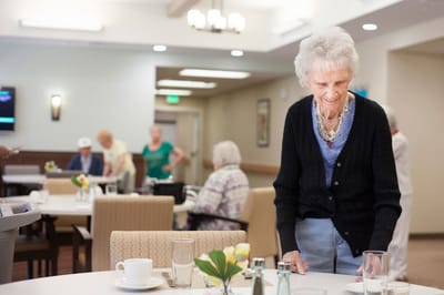 A resident setting the table in a communal dining area