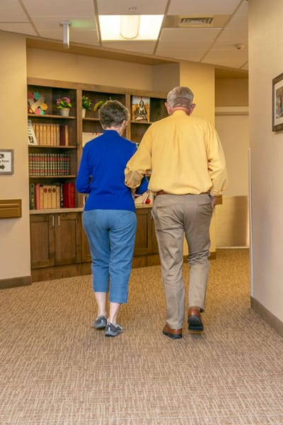 Two residents walking down a hallway in the facility