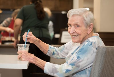 A smiling resident enjoying a drink in the common area