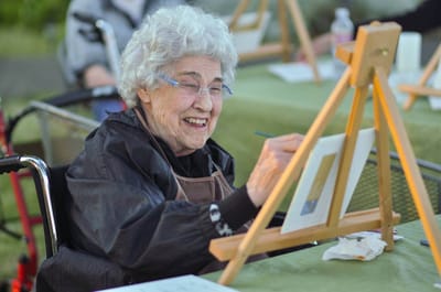 Resident painting outdoors at a communal activity