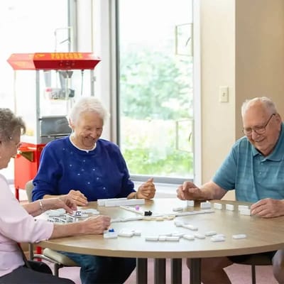 Residents playing dominoes in a bright common area