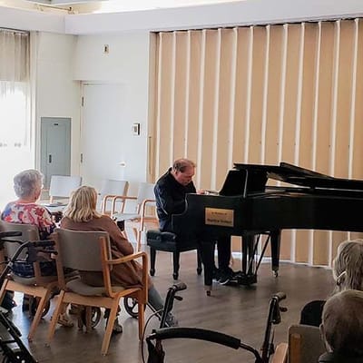 Residents enjoying a piano performance in the activity room