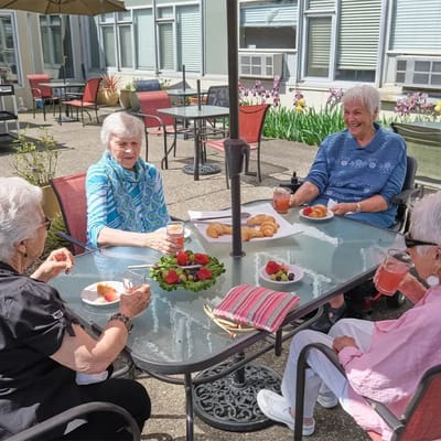 Four residents enjoying drinks and fruit outdoors
