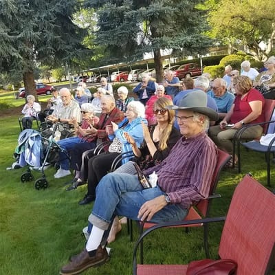 Residents enjoying an outdoor event, clapping and smiling