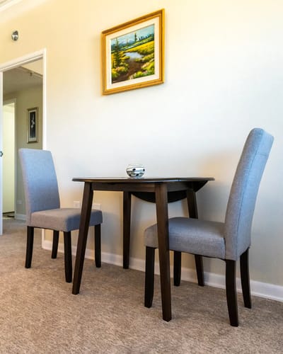 Table and chairs in a cozy room with a painting