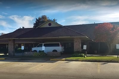 Front entrance of a senior living facility with a van