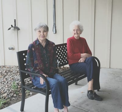 Two senior women sitting on a bench outside