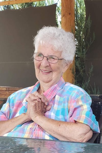 A smiling elderly woman in a colorful shirt