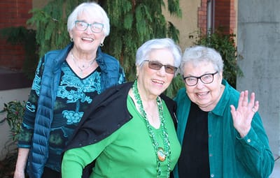 Three smiling senior women posing outdoors