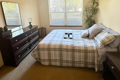 A private resident room with a bed and dresser