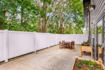 Outdoor seating area with garden beds and a white fence