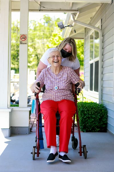 A staff member assisting a smiling resident outdoors