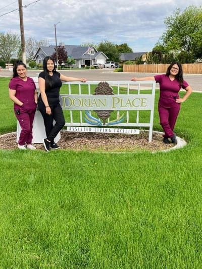 Staff members posing by the facility sign in the yard
