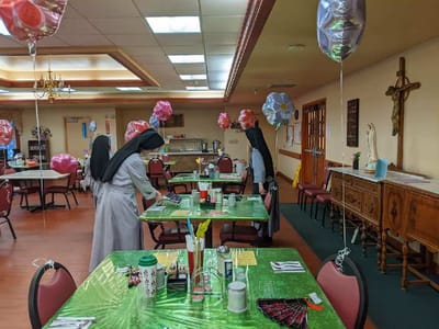 Two staff members setting up a dining area with decorations