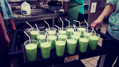 Staff serving green drinks on a cart in the kitchen