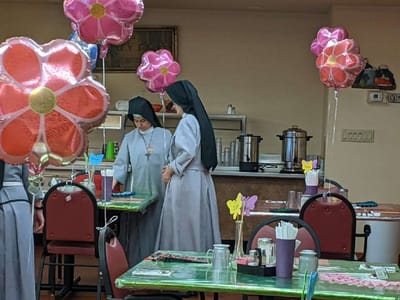 Two women in religious habit decorating a dining area with balloons