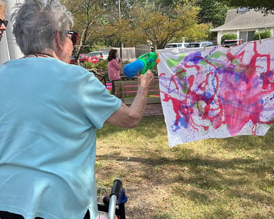 Resident painting with a water gun during an outdoor activity.