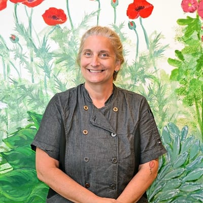 Staff member smiling in front of a floral mural