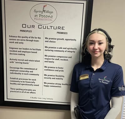 Staff member in a facility interior with values poster